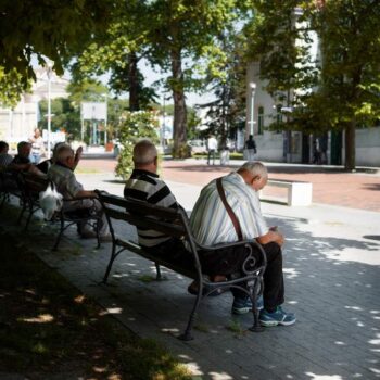 paysage urbain ensoleillé avec hommes assis sur des bancs