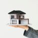 Main dans laquelle se trouve une maison à deux étages