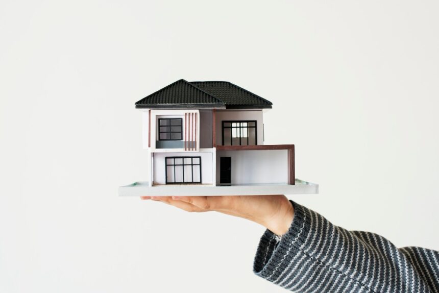Main dans laquelle se trouve une maison à deux étages