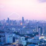 Vue panoramique d’une ville intelligente au coucher du soleil avec icônes de cloud computing et connexion sans fil