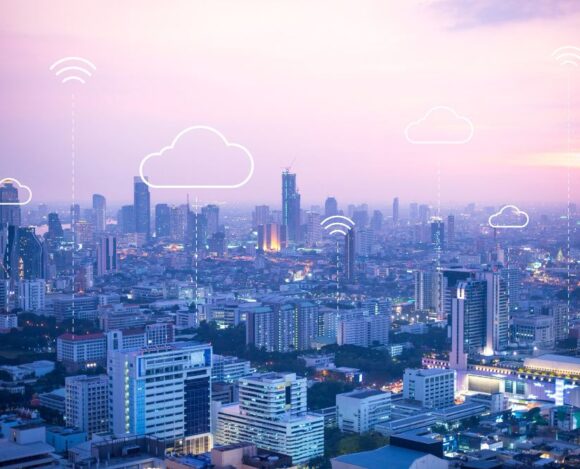 Smart city connectée et technologies cloud au cœur de la métropole Vue panoramique d’une ville intelligente au coucher du soleil avec icônes de cloud computing et connexion sans fil
