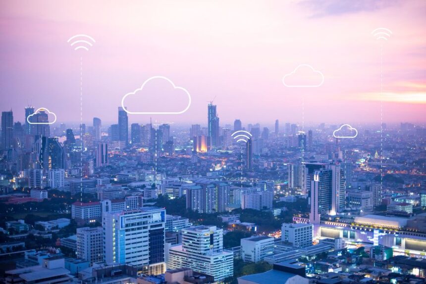 Vue panoramique d’une ville intelligente au coucher du soleil avec icônes de cloud computing et connexion sans fil